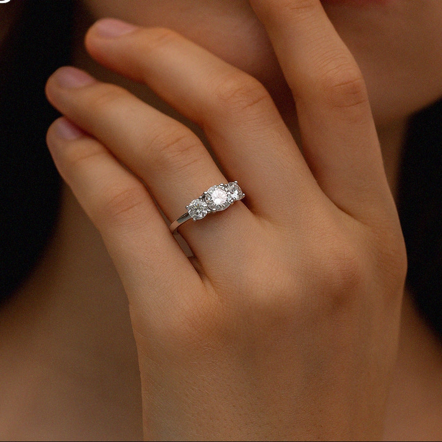 Round moissanite three-stone engagement ring close-up on hand