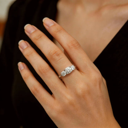 Round moissanite three-stone engagement ring worn on hand